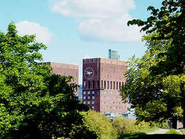 Oslo rådhus med trær i forgrunnen.