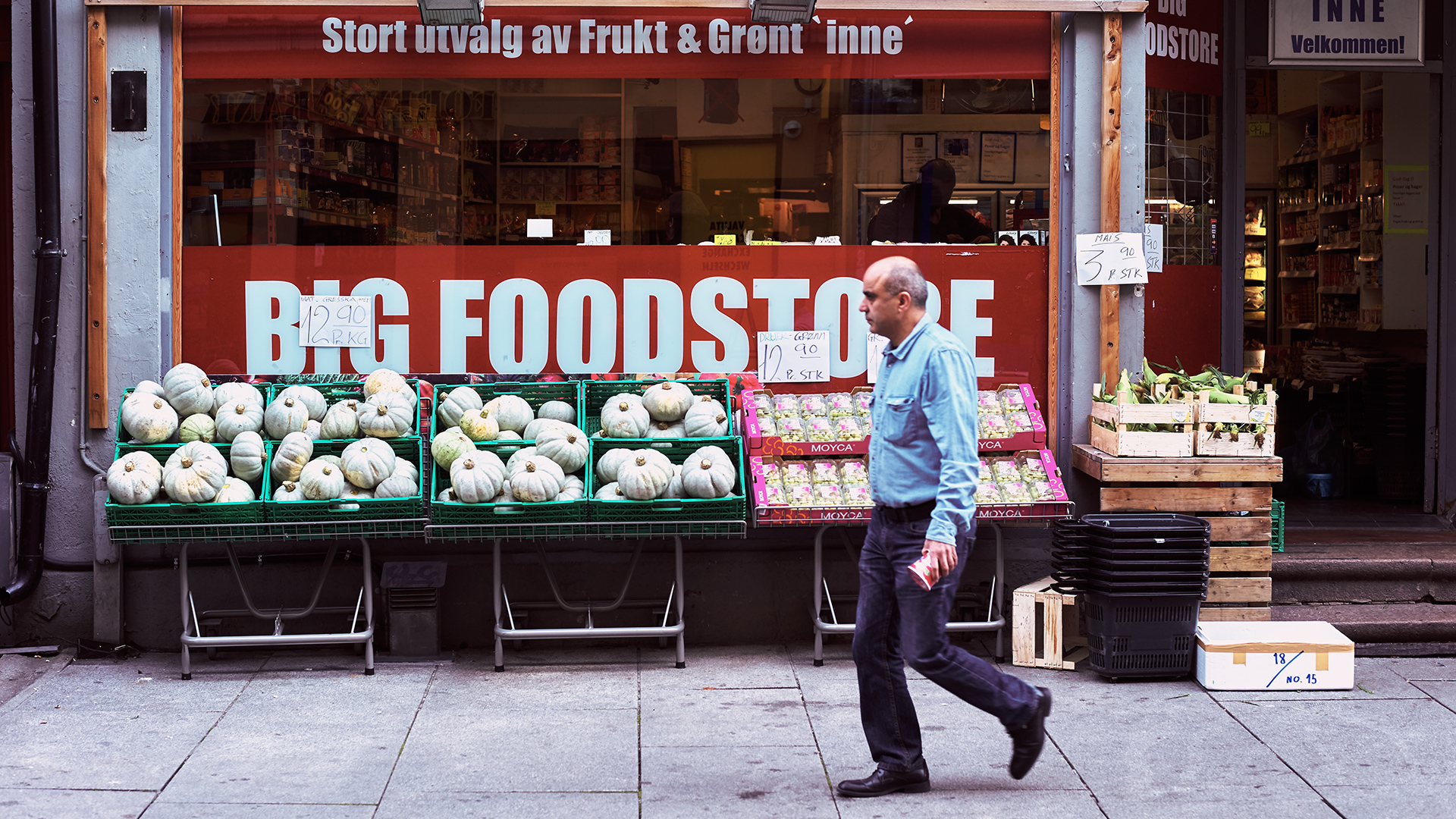 Person som går forbi en frukt og grønt butikk.