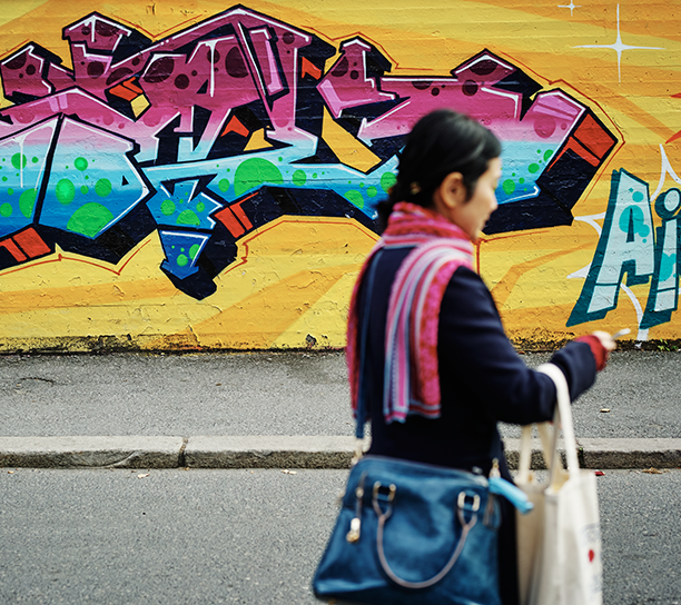 Kvinne i forgrunnen, grafittivegg i bakgrunnen.
